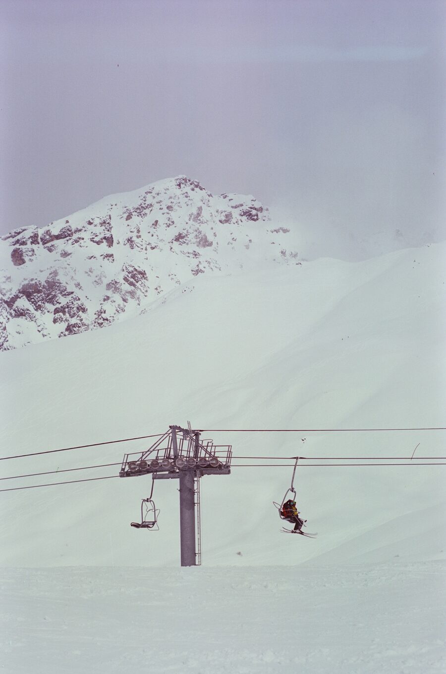 Chairlift climbing into a pale snowy ridge